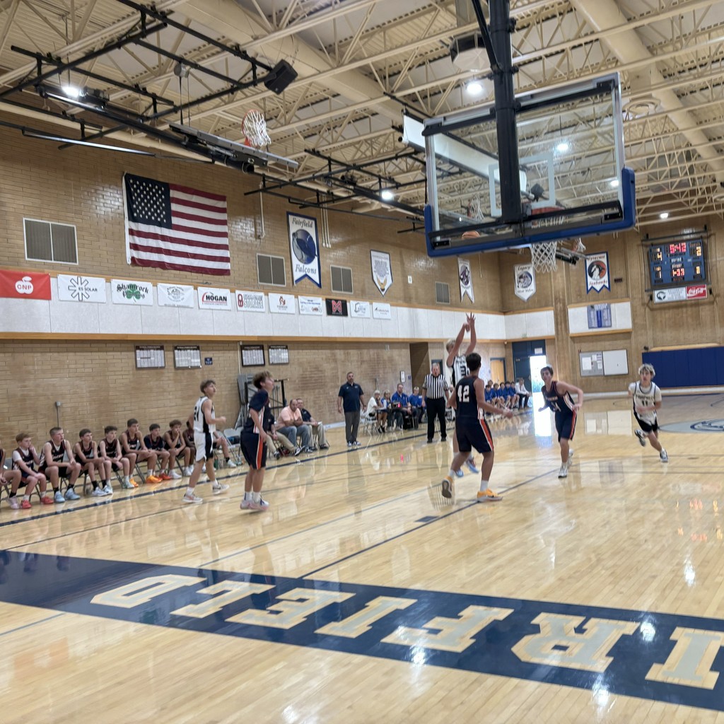 Fairfield's basketball team, wearing white, competing against Syracuse, wearing Navy Blue.