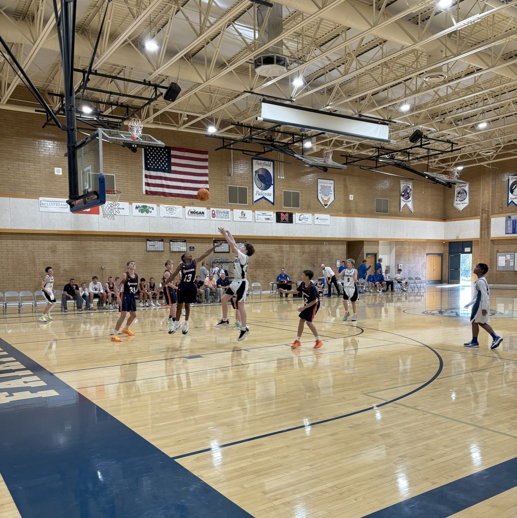 Fairfield's basketball team, wearing white, competing against Syracuse, wearing Navy Blue.