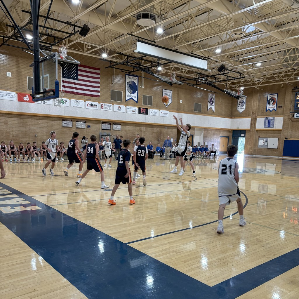 Fairfield's basketball team, wearing white, competing against Syracuse, wearing Navy Blue.