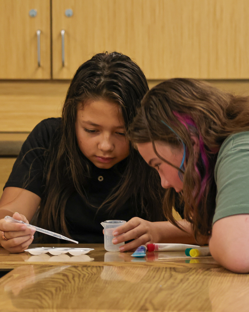 Students using a pipet to pull liquid from a beaker.