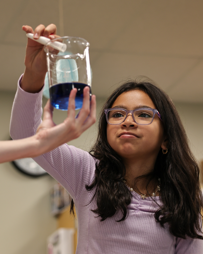 A student holding a beaker with blue liquid.