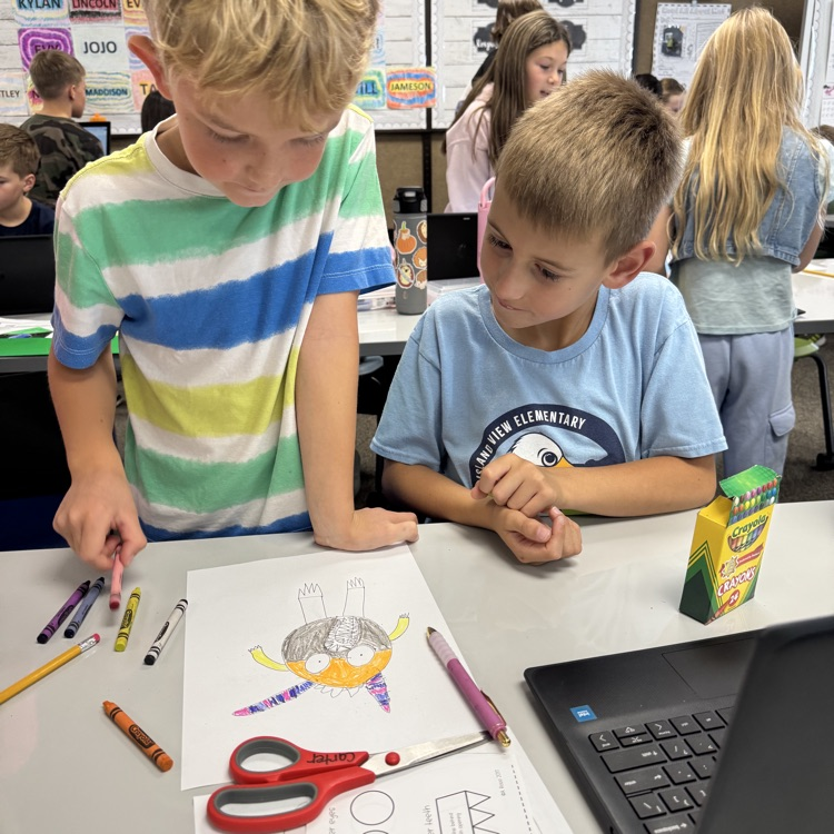 two boys looking down at a drawing in crayon
