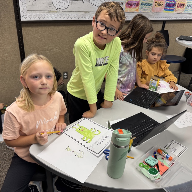 students sitting around a desk with drawings in front of them