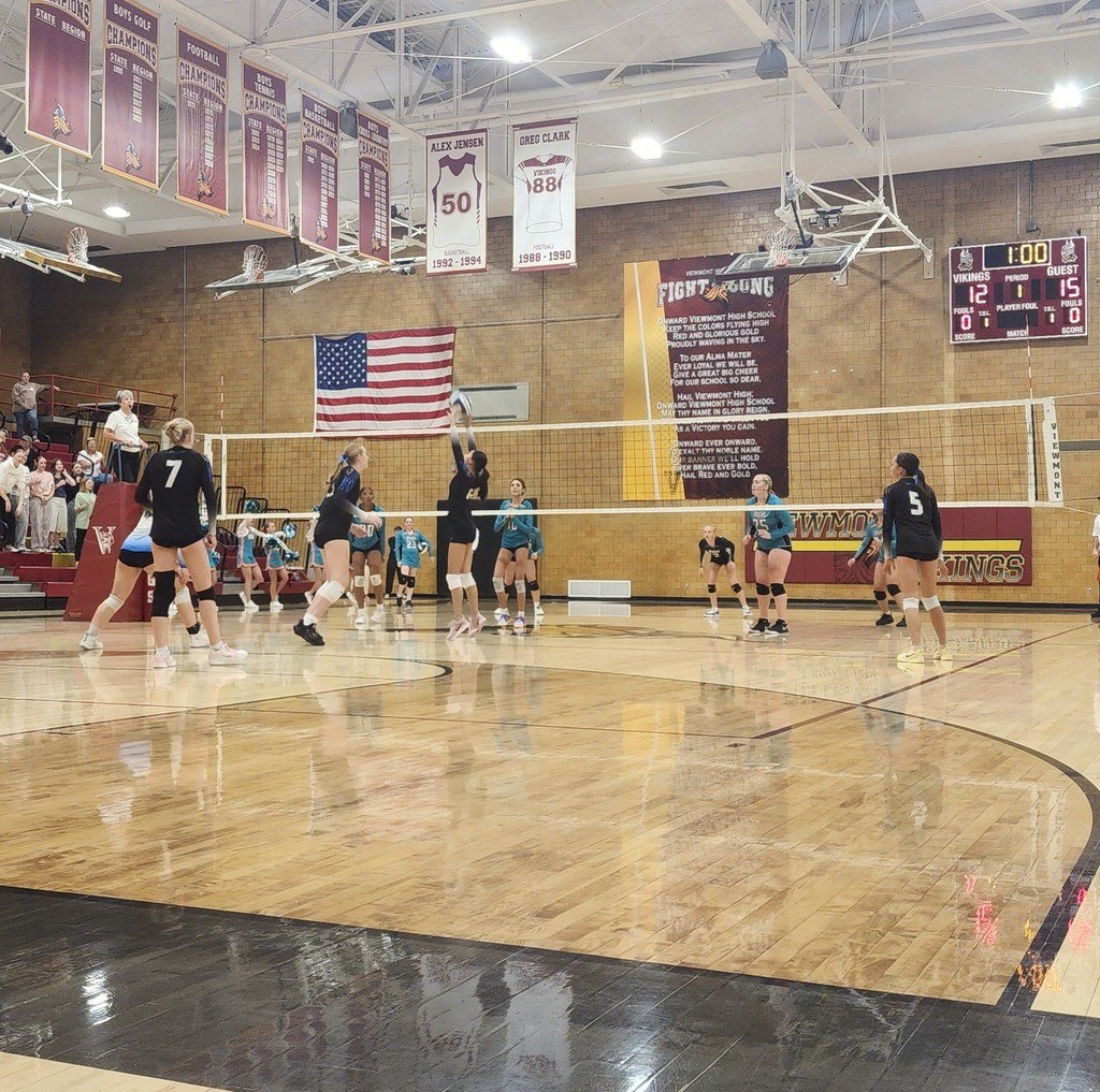 Fairfield's setter is setting the ball.  Fairfield's team is on the near side of the net, and Horizon's team is on the far side.