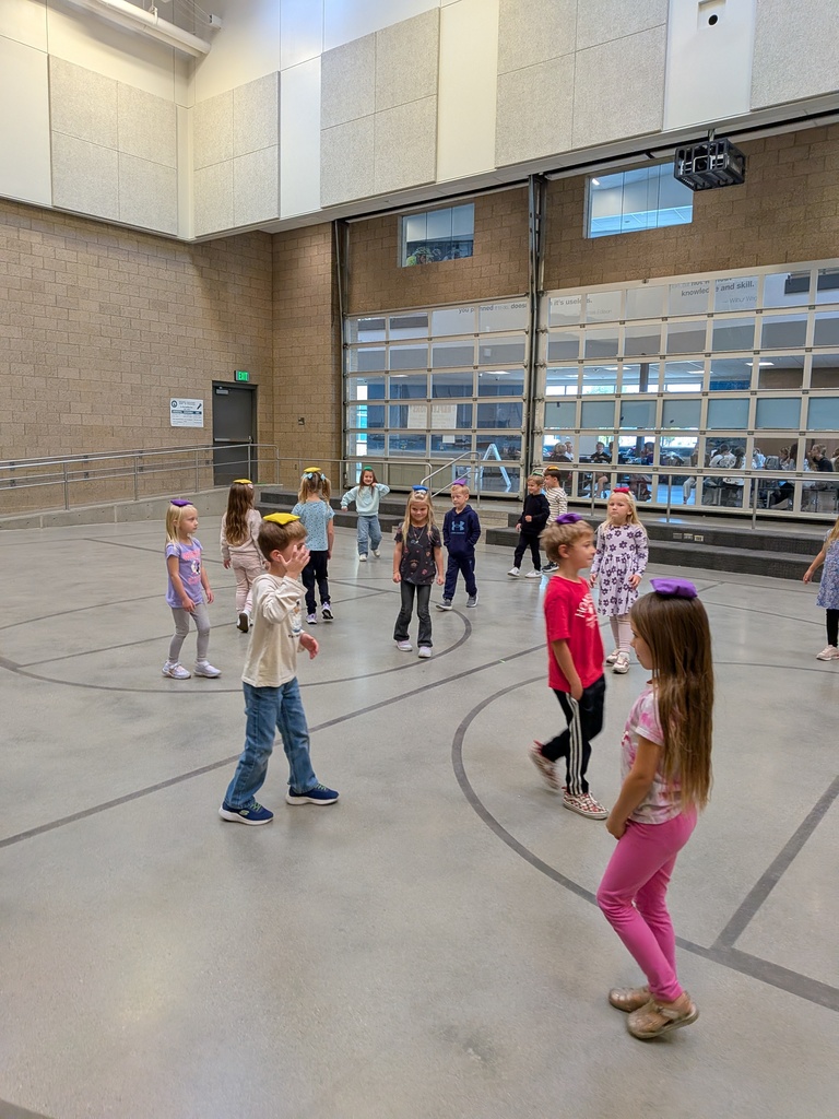Students walking around the school gym with small beanbags balanced on top of their heads.