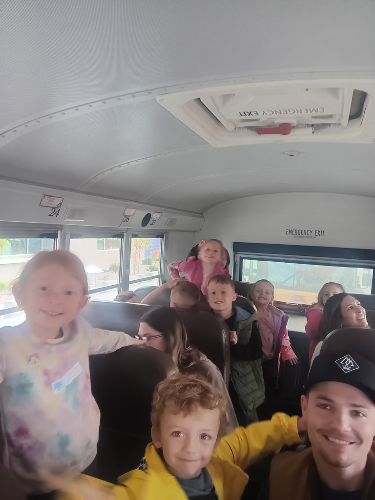 a group of children and a man on a bus smiling at the camera