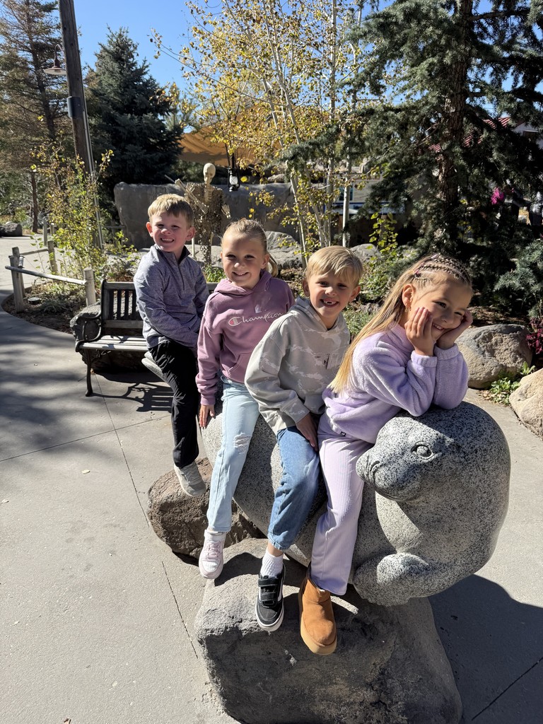 students pictured sitting on a seal statue at the zoo
