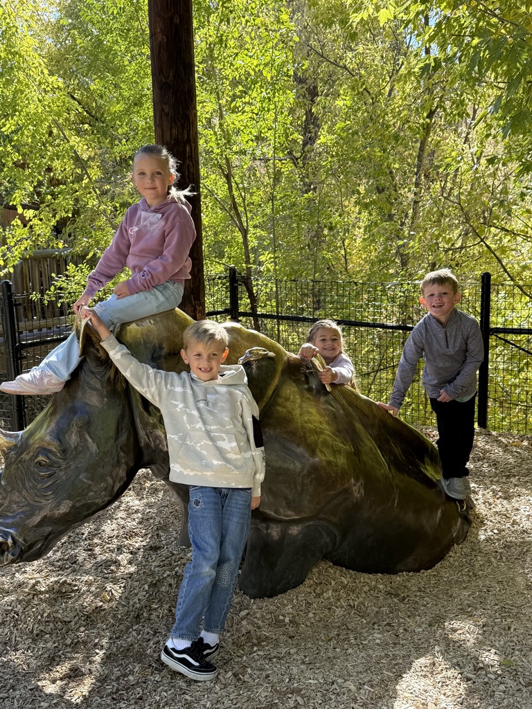 students pictured on a rhinoceros statue at the zoo