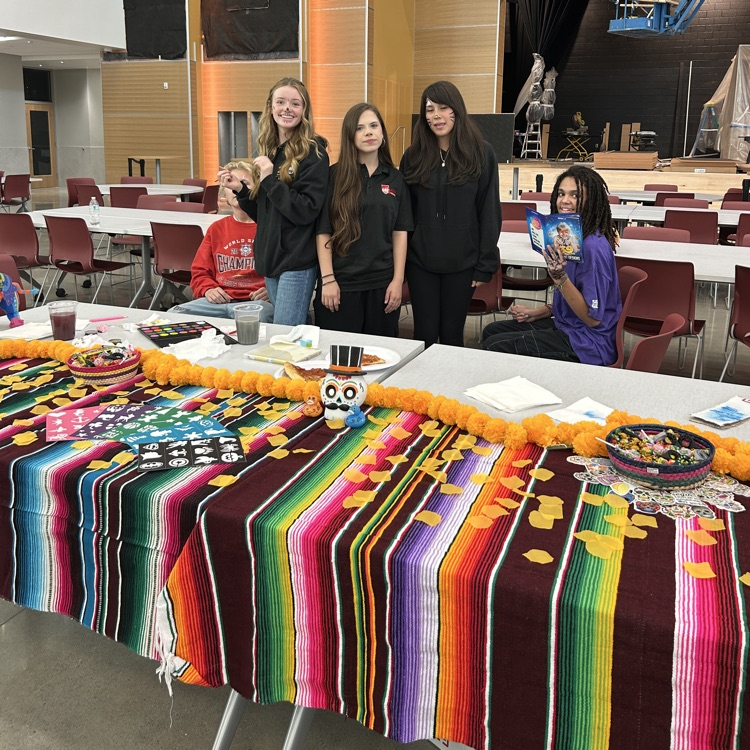 Students standing behind a table with a colorful cloth