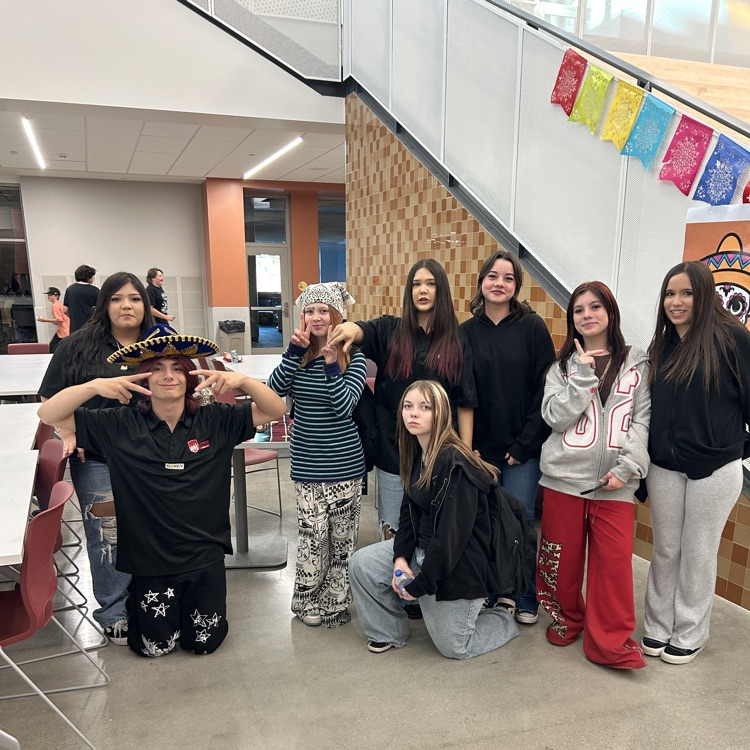 Eight student stand together with colorful flags behind them