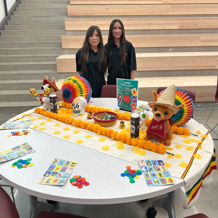Two students stand behind a table with a bingo game
