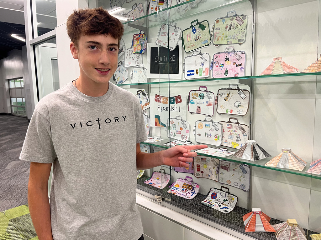 A student points at their art work.