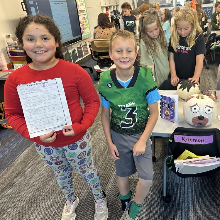 girl in red shirt smiles holding paper and boy in green jersey smiles