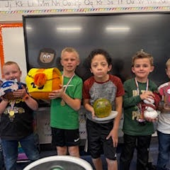 4 boys holding decorated pumpkins