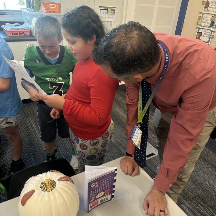 man leans over listening to girl student read from her paper
