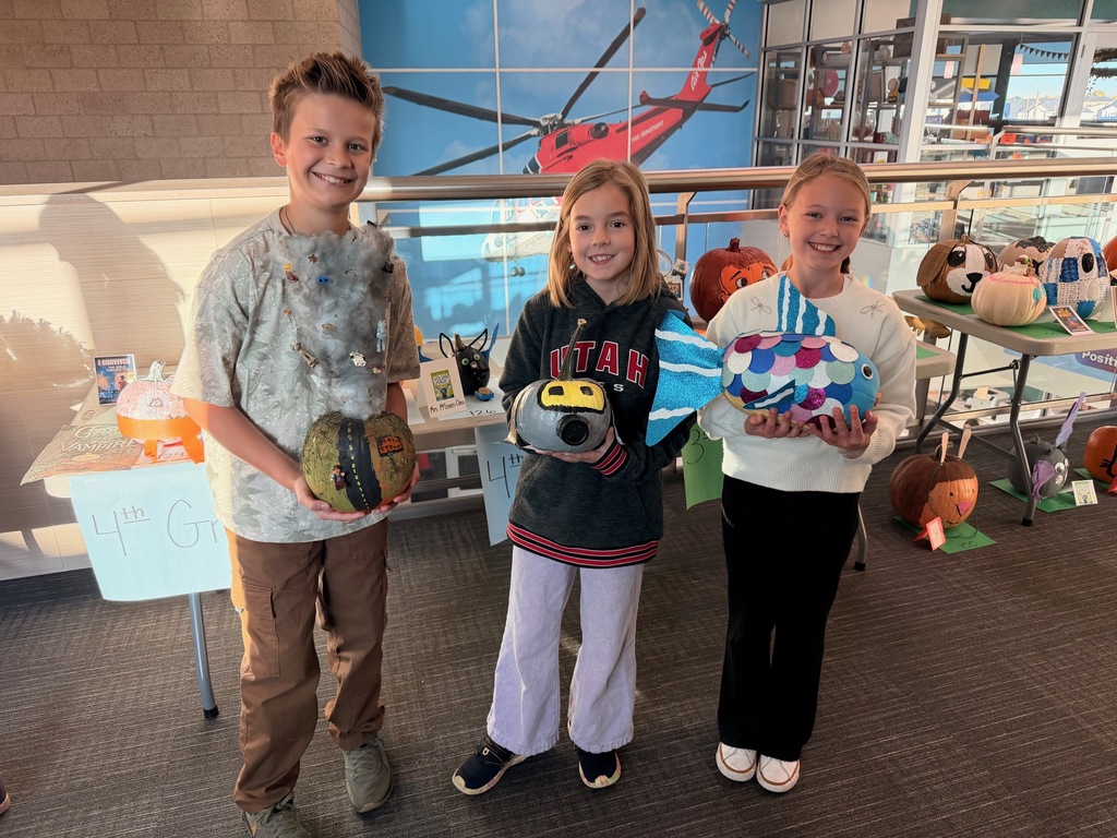 students posing with decorated pumpkins