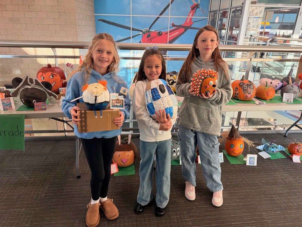 students posing with decorated pumpkins