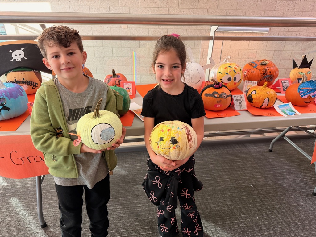 students posing with decorated pumpkins