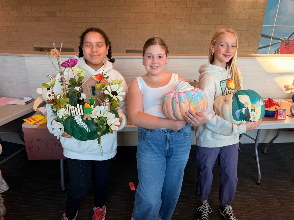 students posing with decorated pumpkins