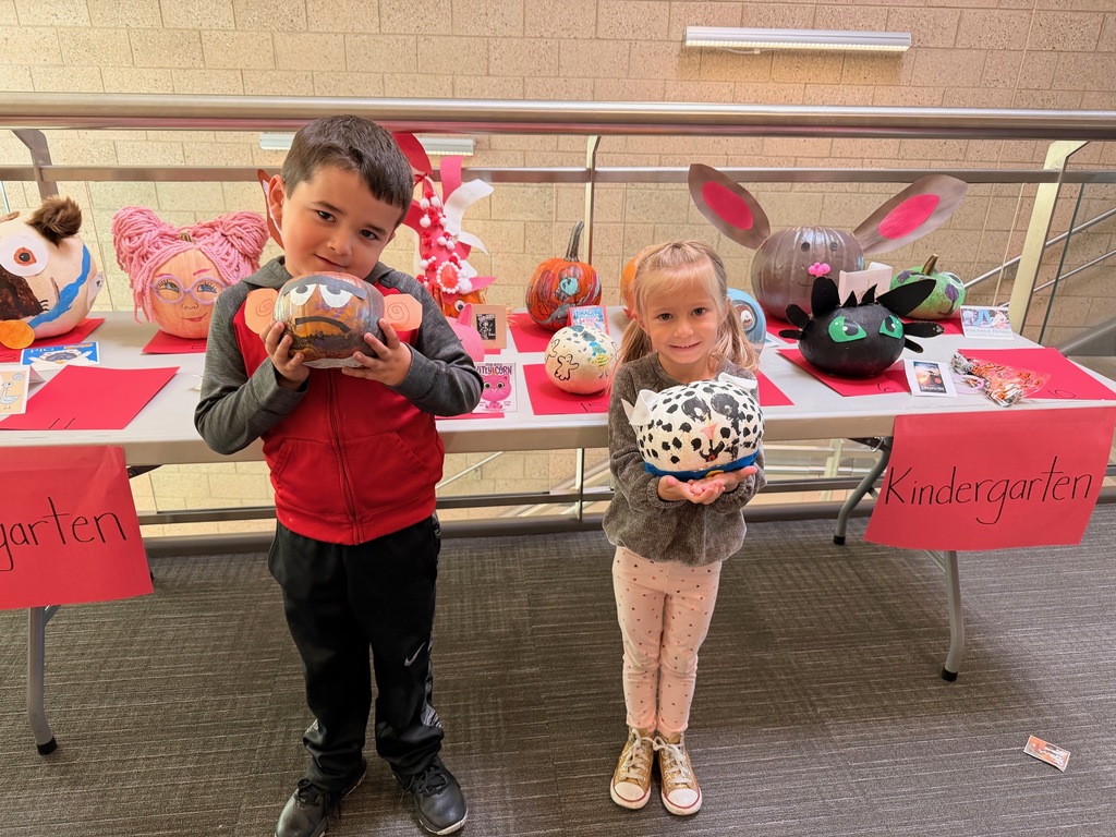 students posing with decorated pumpkins