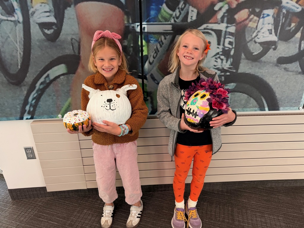 students posing with decorated pumpkins