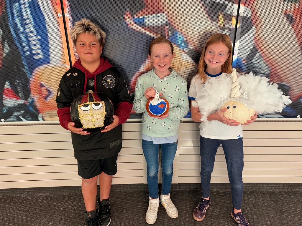 students posing with decorated pumpkins