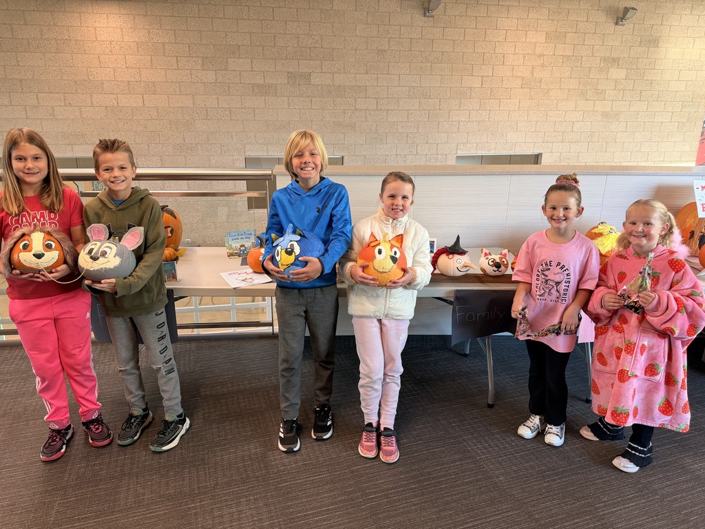 students posing with decorated pumpkins