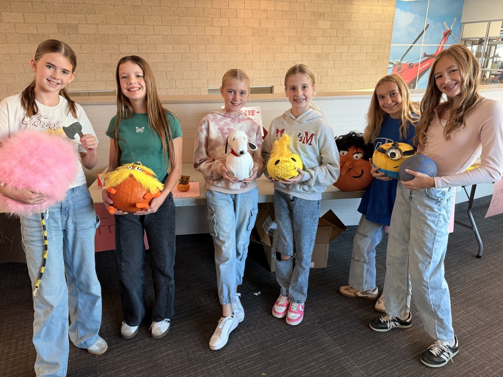 students posing with decorated pumpkins