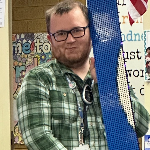 Mr. Hansen posing with a Lego board piece 