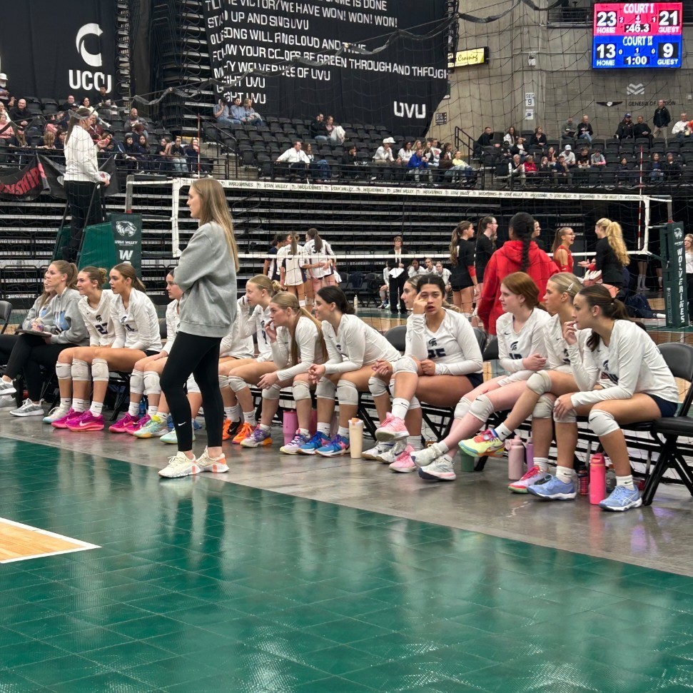 Lancer volleyball coach and players on the bench watching the game