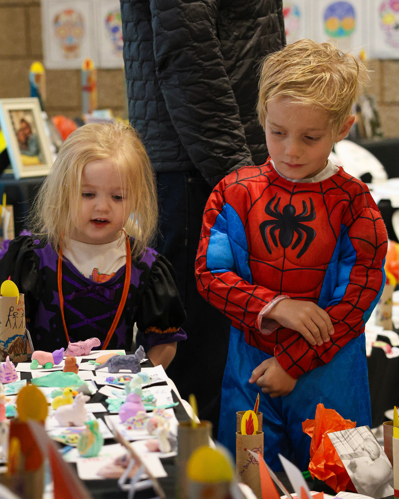 Two students dressed in Halloween costumes look at items on the ofrenda at Canyon Creek Elementary.