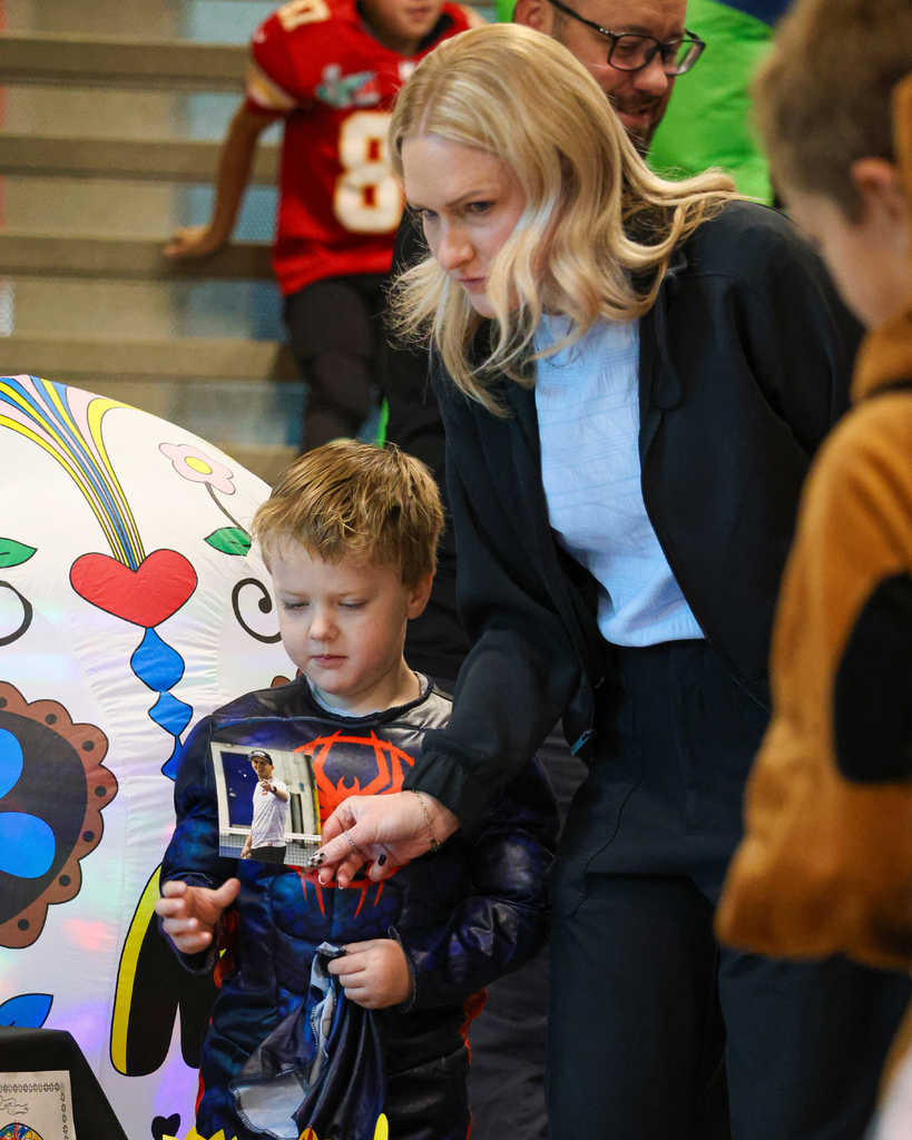 A parent hands a photo to a student to put onto the ofrenda at Canyon Creek Elementary.