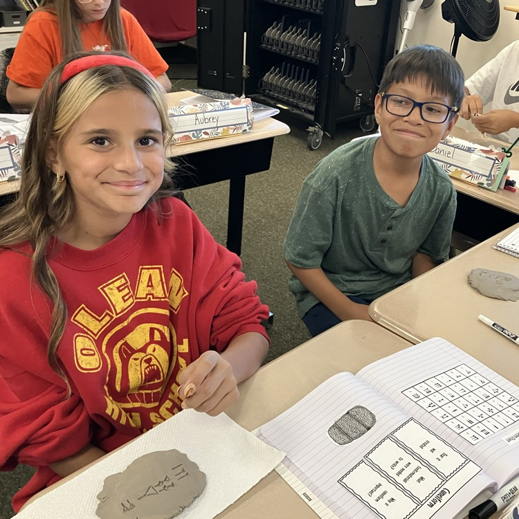 Students curving names into clay