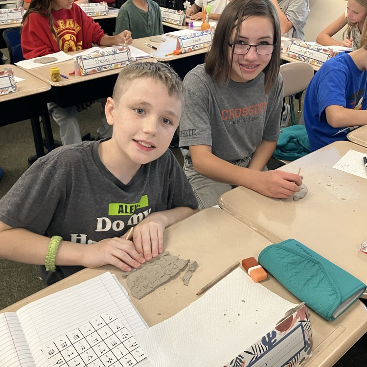 Students carving names into clay