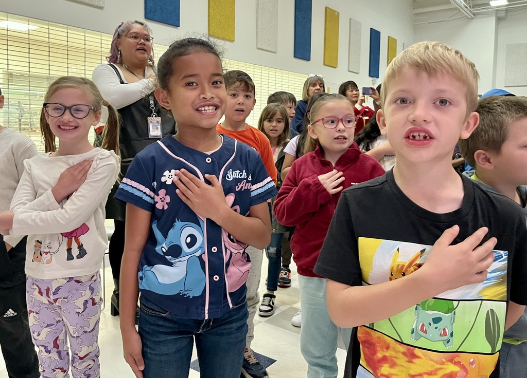 Two students smiling and putting their hands over their heart. 