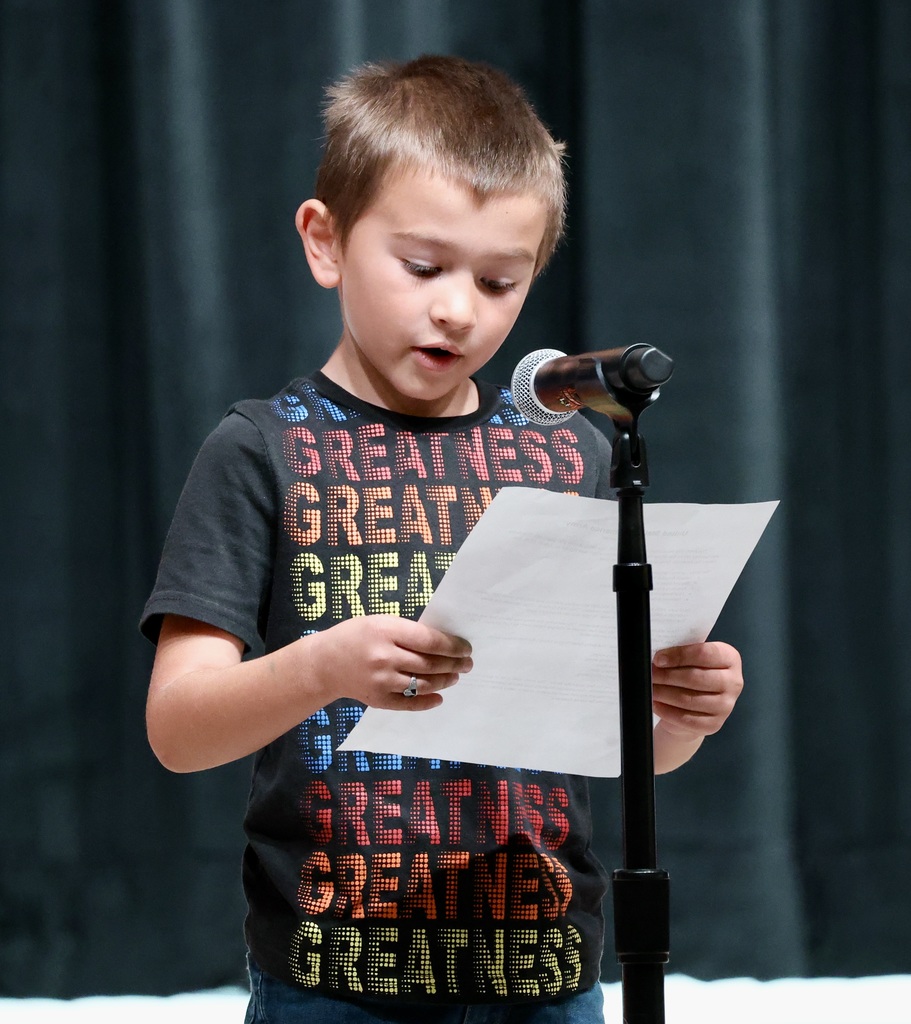 A student reads a paper while talking into a mic. 