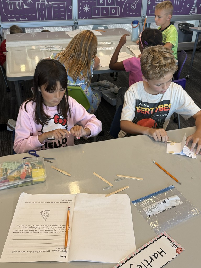 a boy and girl using popsicle sticks and paper to make something