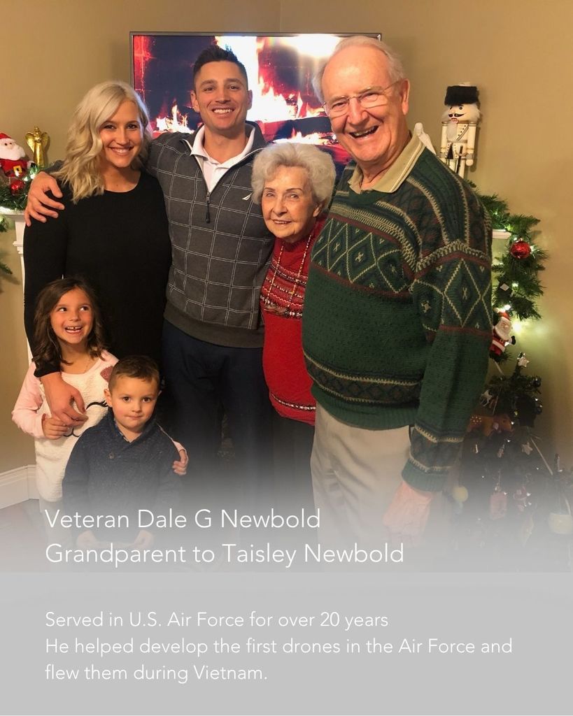 A family of grandparents, parents, and two children standing in front of a Christmas tree
