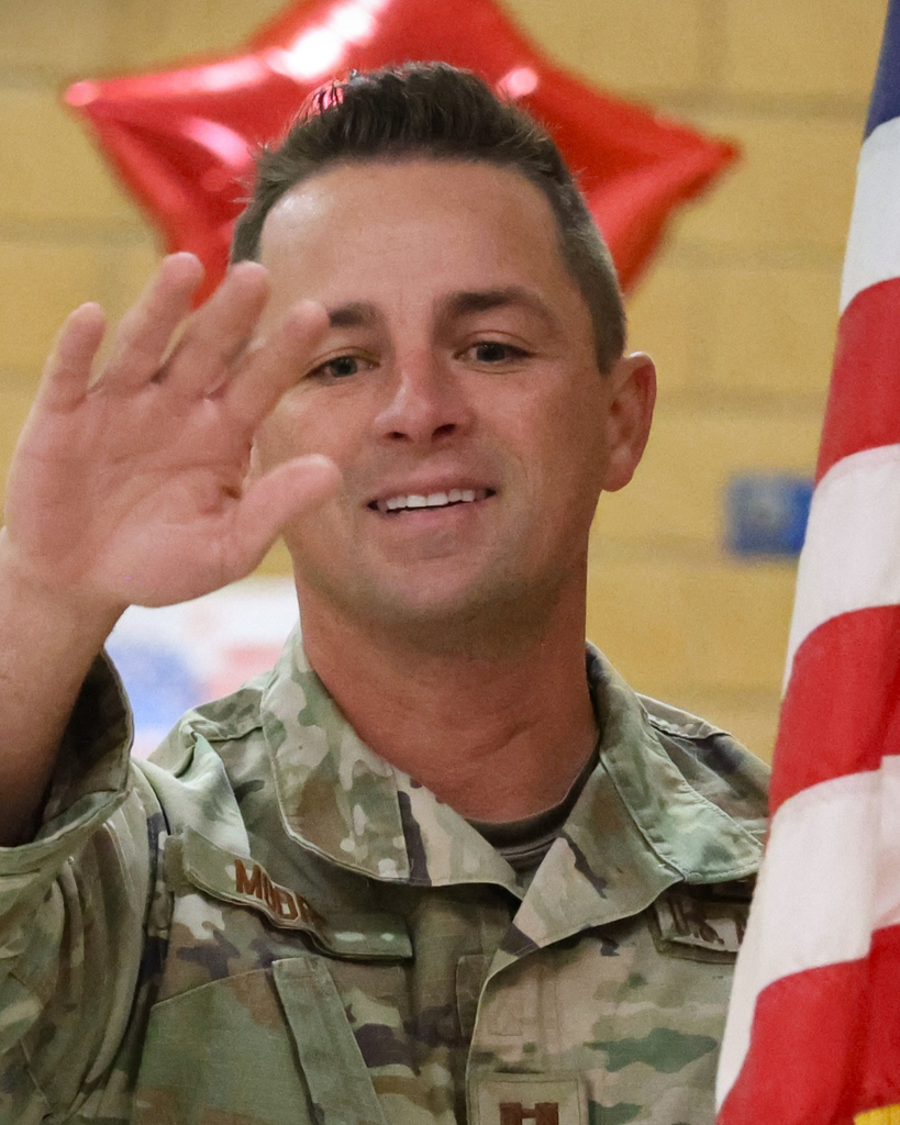 An army man waves and smiles. 