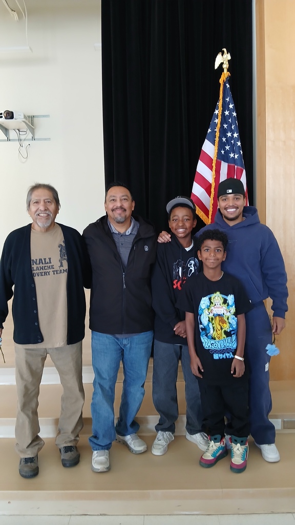 2 students posing with their military family members in front of the flag during our veterans day assembly