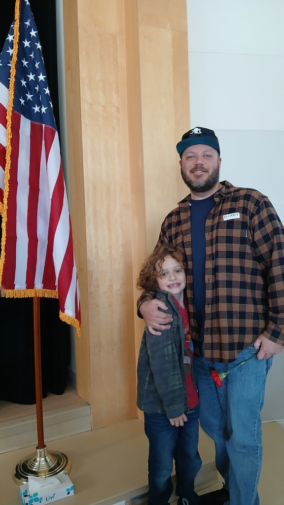 student hugs his dad as they both pose in front of the flag.