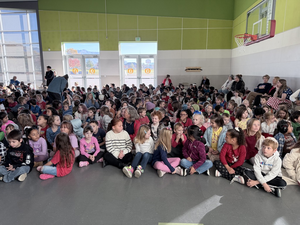 Group picture showing Doxey students sitting on the floor of the gym while they waited for the assembly to begin