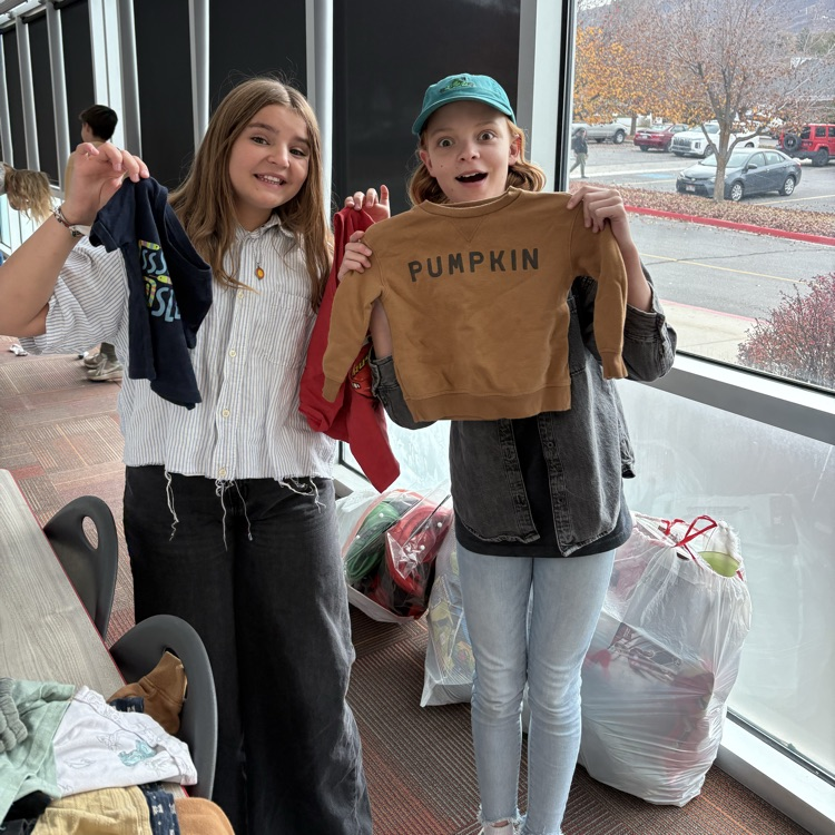 two students holding up clothes