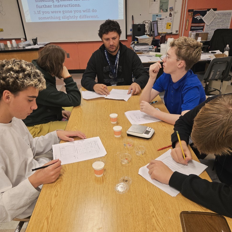 four students and a teacher assistant working on their lab