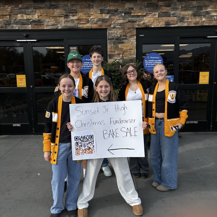 students holding a sign to the bake sale