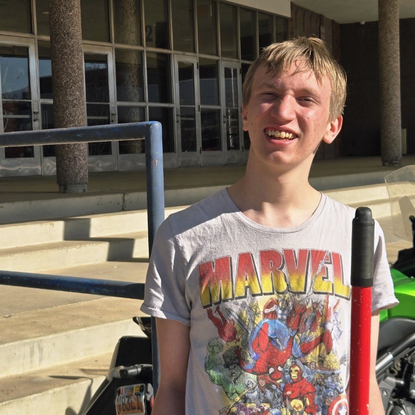 students smiling for a picture while standing in the sun and holding a shovel
