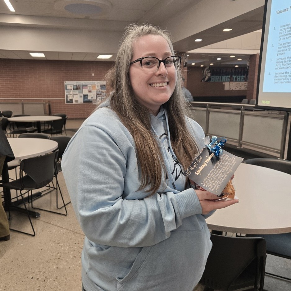 Ms. Hansen's holding her teacher Bright Spot Award and smiling for the camera