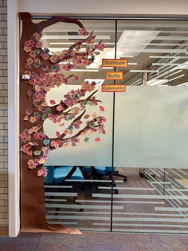 Paper tree taped to glass wall with fall leaf sticky notes sharing gratitude. Gratitude tree. 