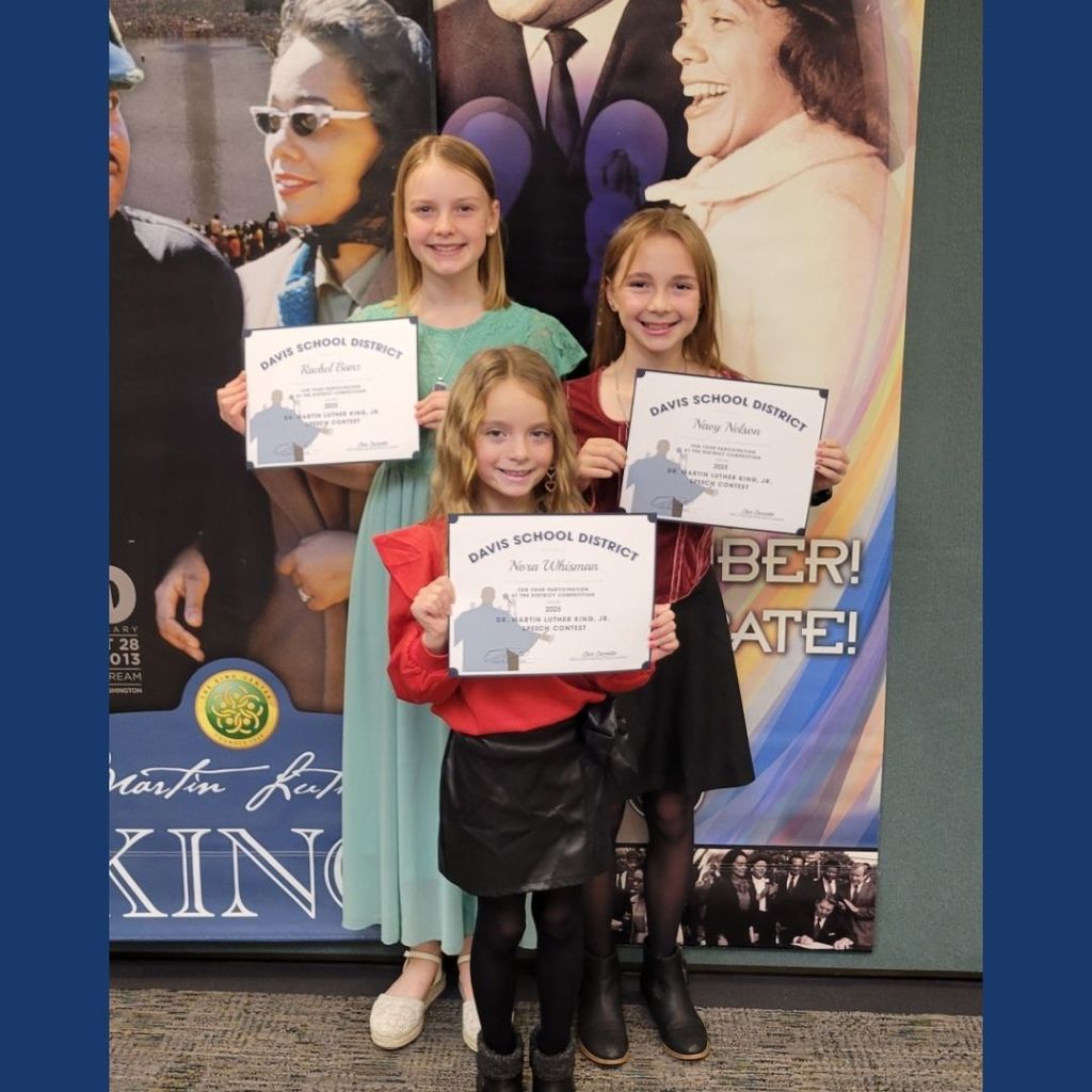 Students holding certificates in front of an MLK backdrop.