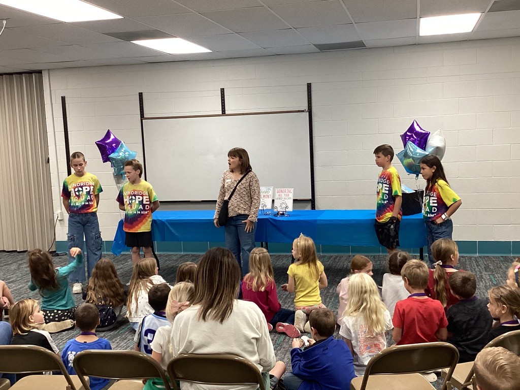 Kids and one adult standing in front of a small group presenting awards